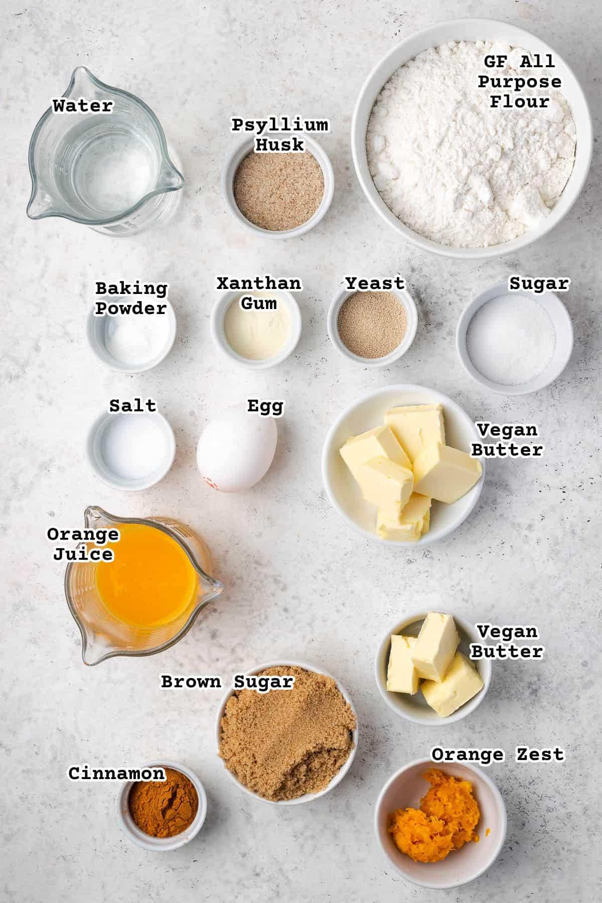 Ingredients for orange cinnamon rolls sitting on a white counter.