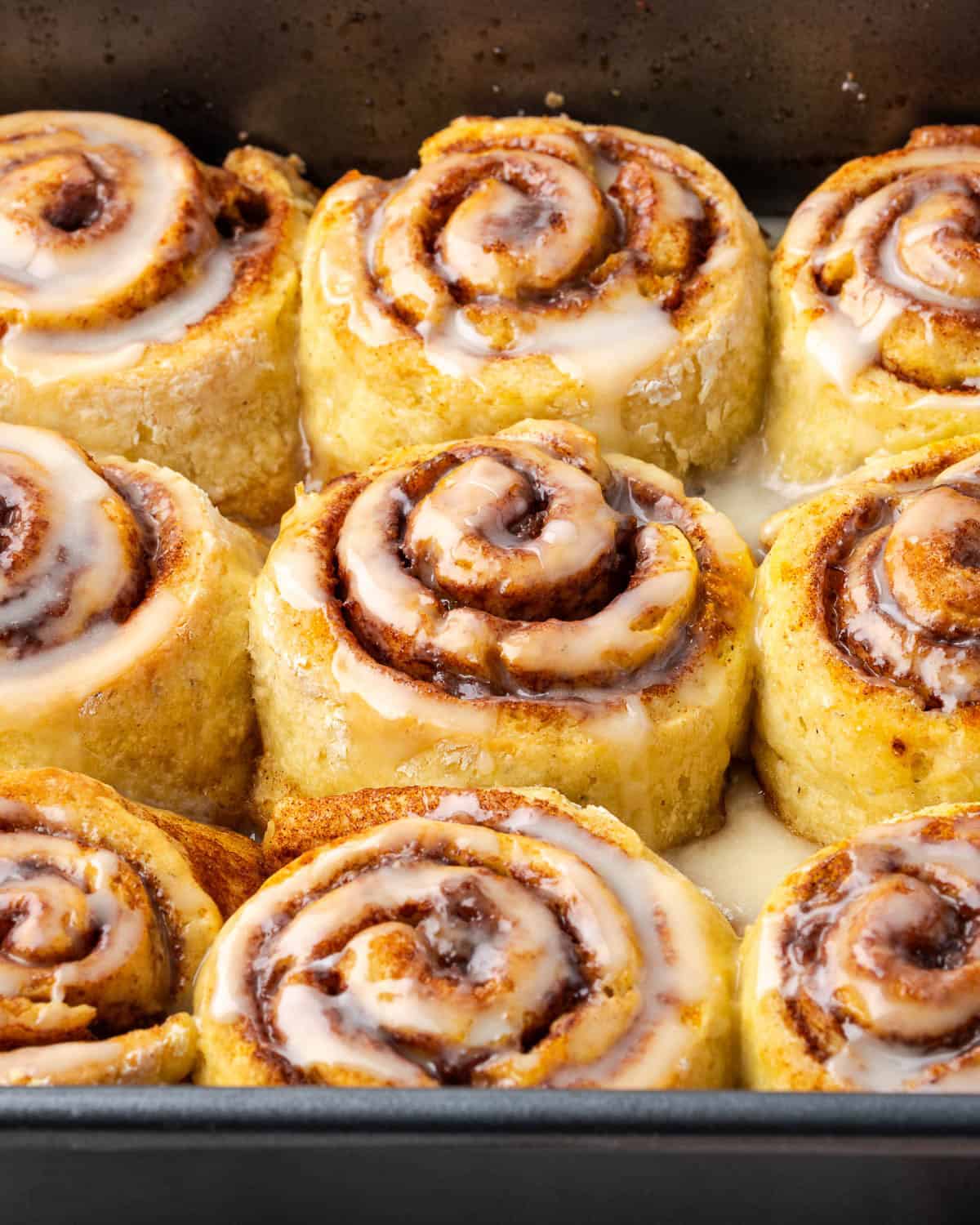 A pan of orange cinnamon rolls covered with orange glaze.