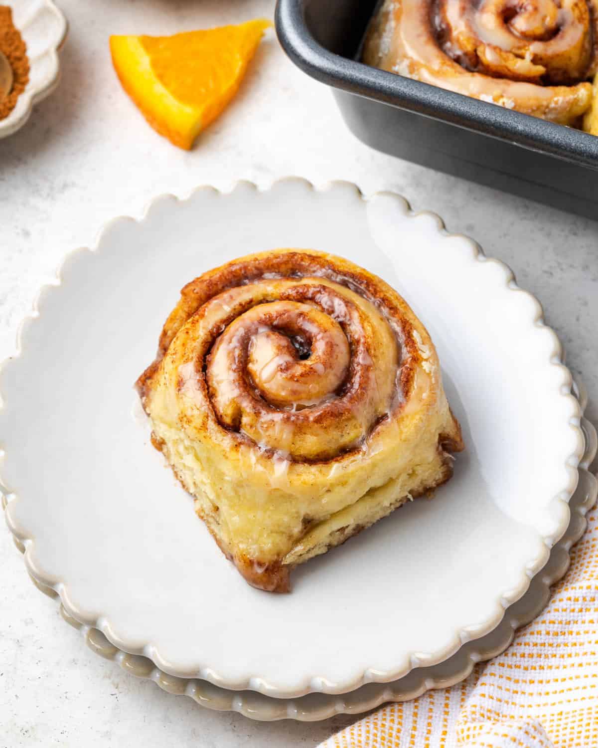 A gluten free orange cinnamon roll sitting on a small serving plate.