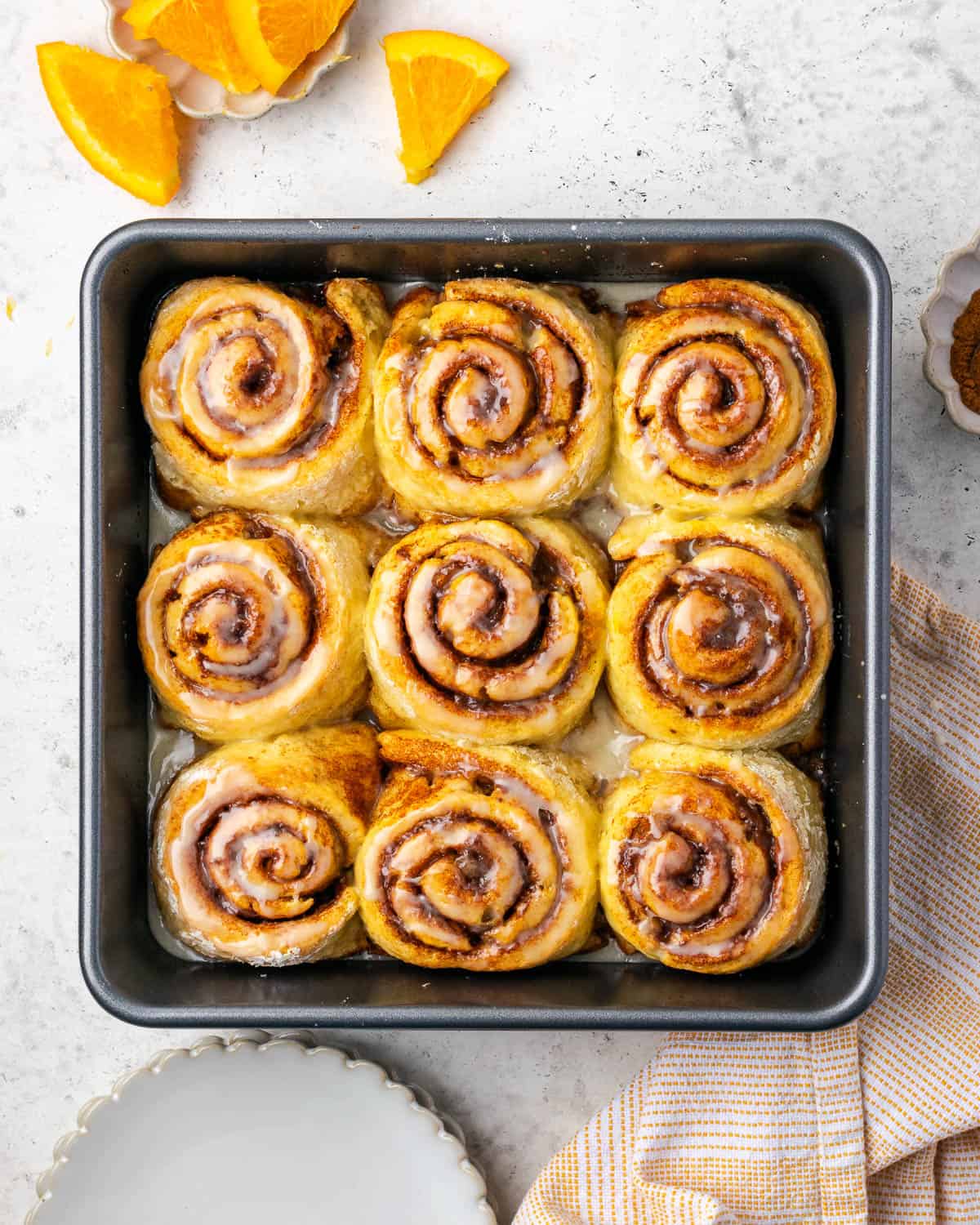 A pan of orange cinnamon rolls sitting on a white countertop.