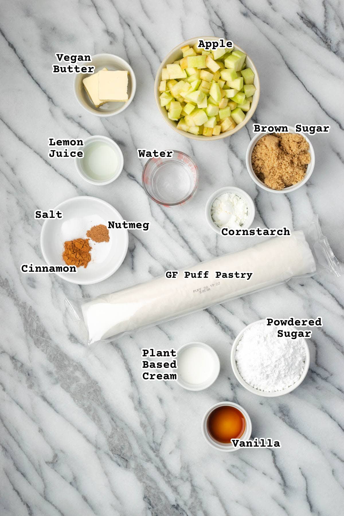 Ingredients for puff pastry apple turnovers sitting on a marble countertop. 
