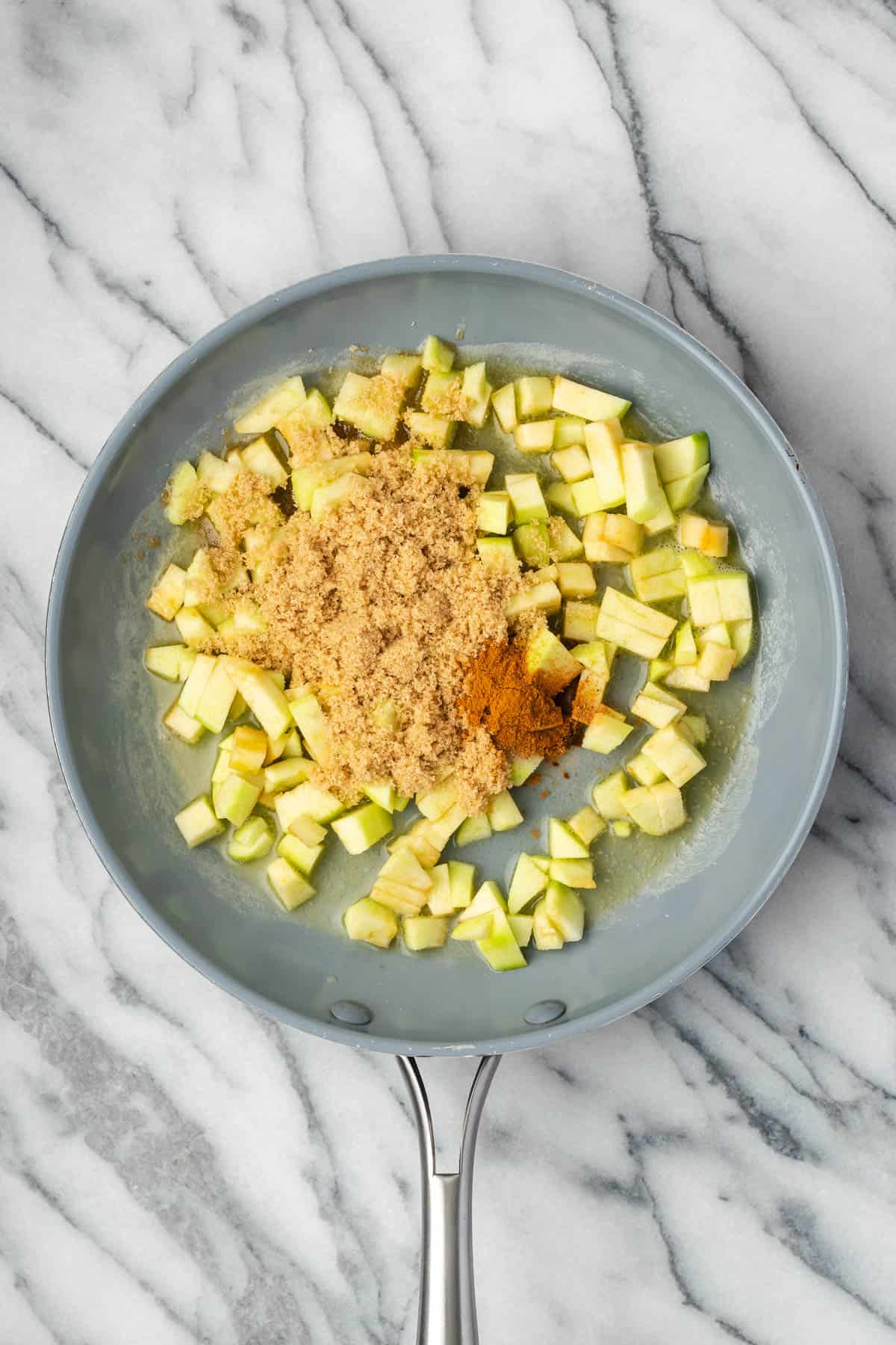 Diced apples, brown sugar, and spices combined in a large skillet. 