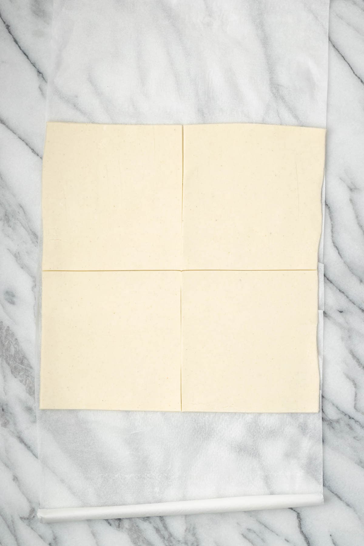 A sheet of puff pastry cut into four squares.