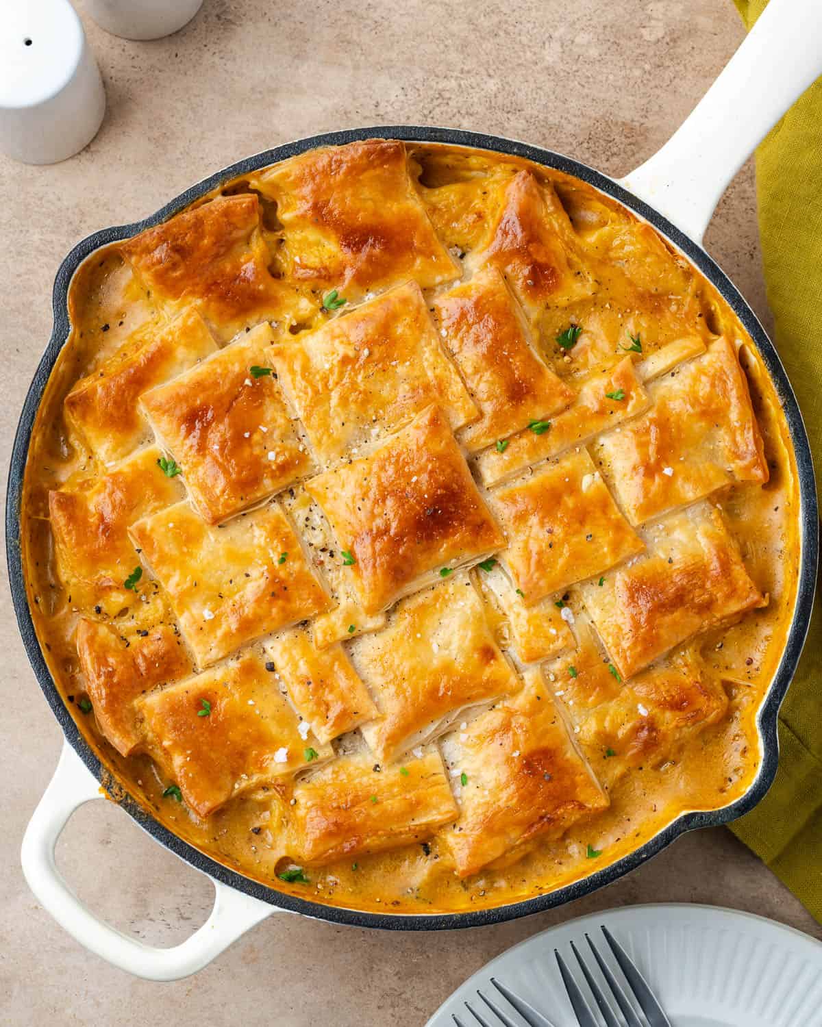 A freshly baked veggie pot pie topped with a golden brown puff pastry crust sitting on a table.