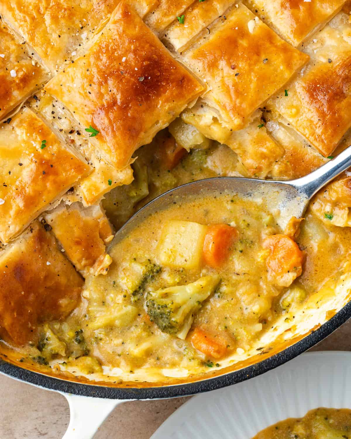 A serving spoon scooping into a pan of veggie pot pie.