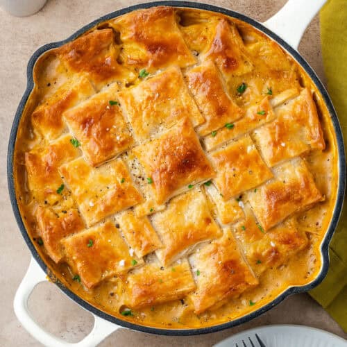 A veggie pot pie with a golden brown puff pastry crust sitting on a table.