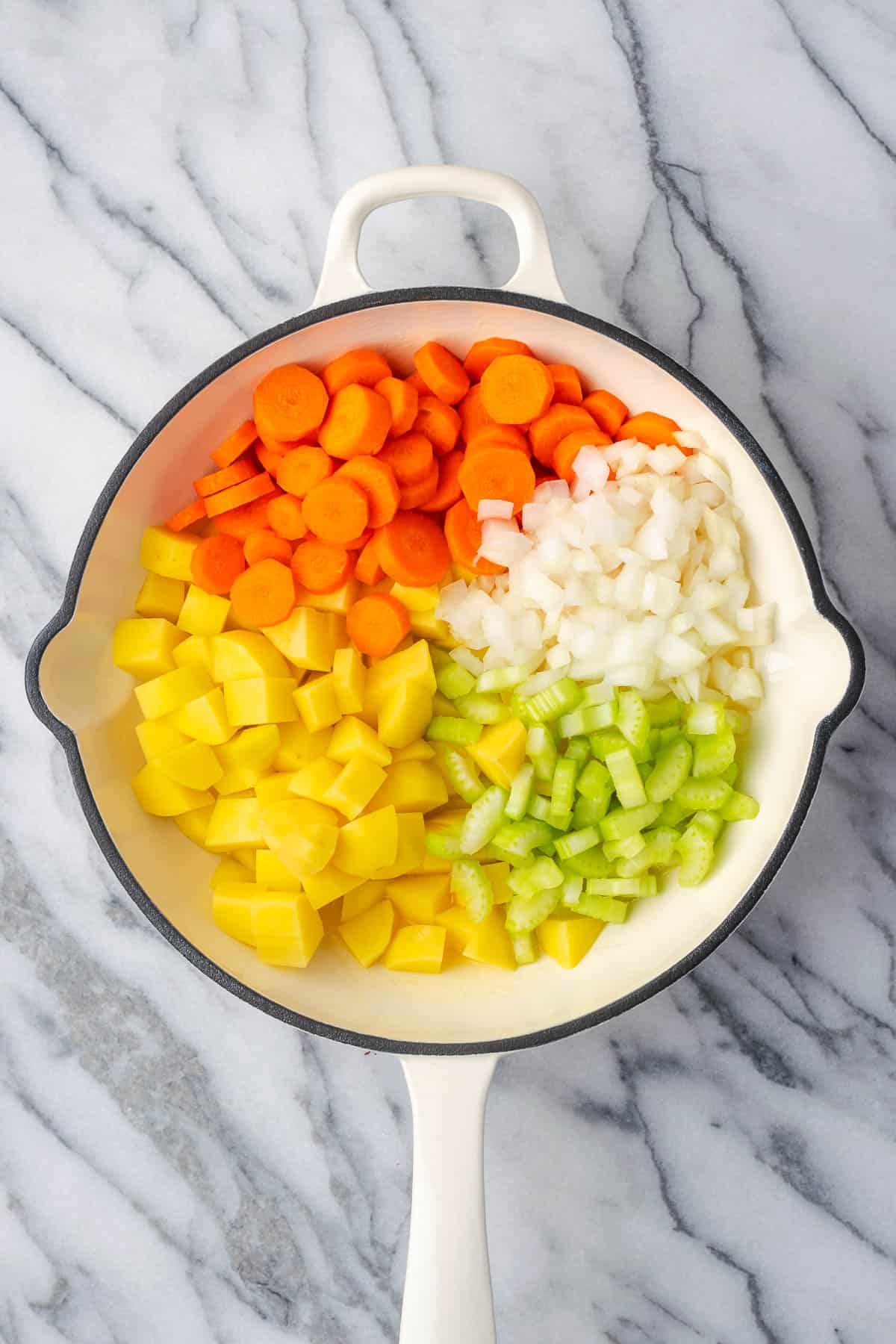 Carrots, potatoes, onions and celery combined in a cast iron skillet.