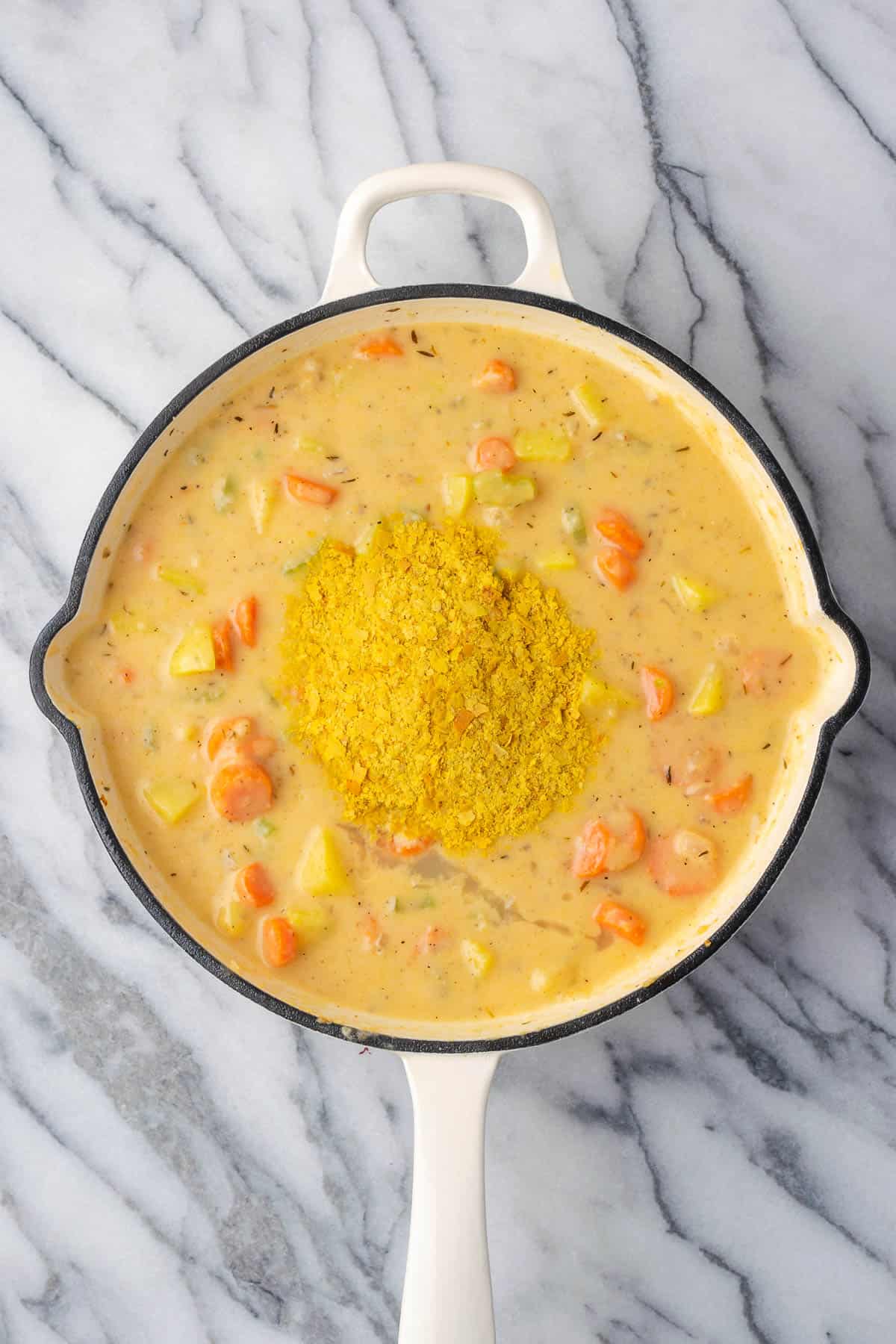 Nutritional yeast and lemon juice being stirred into the pot pie filling.