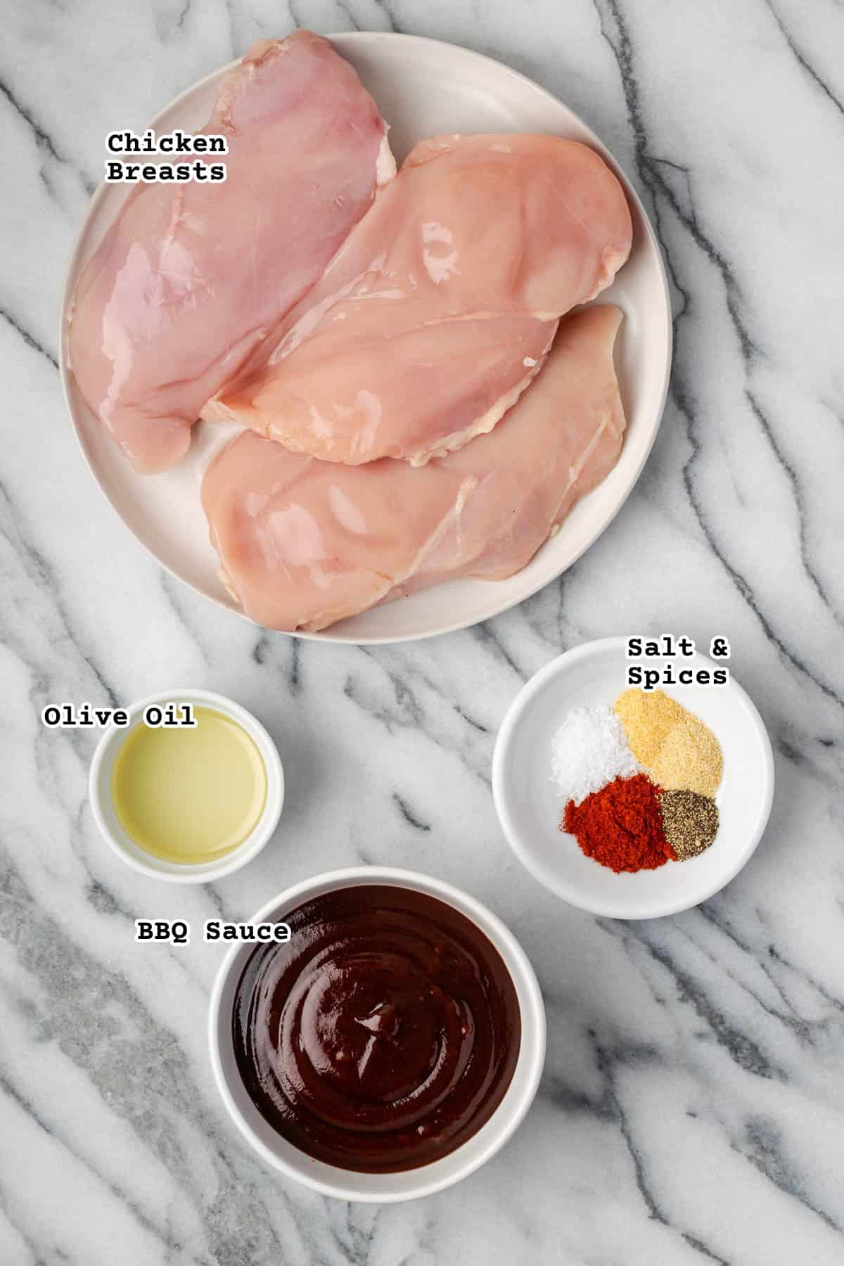 Ingredients for barbecue chicken breasts sitting on a marble counter. 