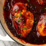 Several baked bbq chicken breasts in a cast iron pan.