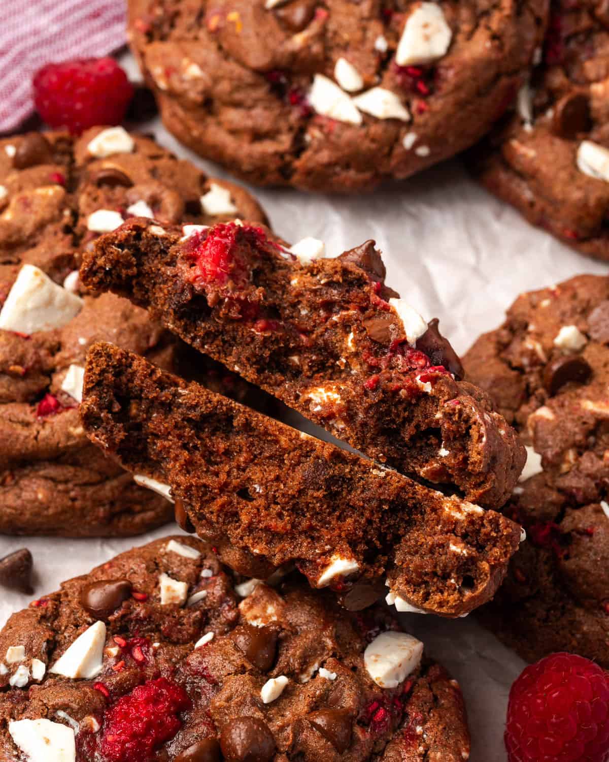 A chocolate raspberry cookie broken in half showing how thick they are. 