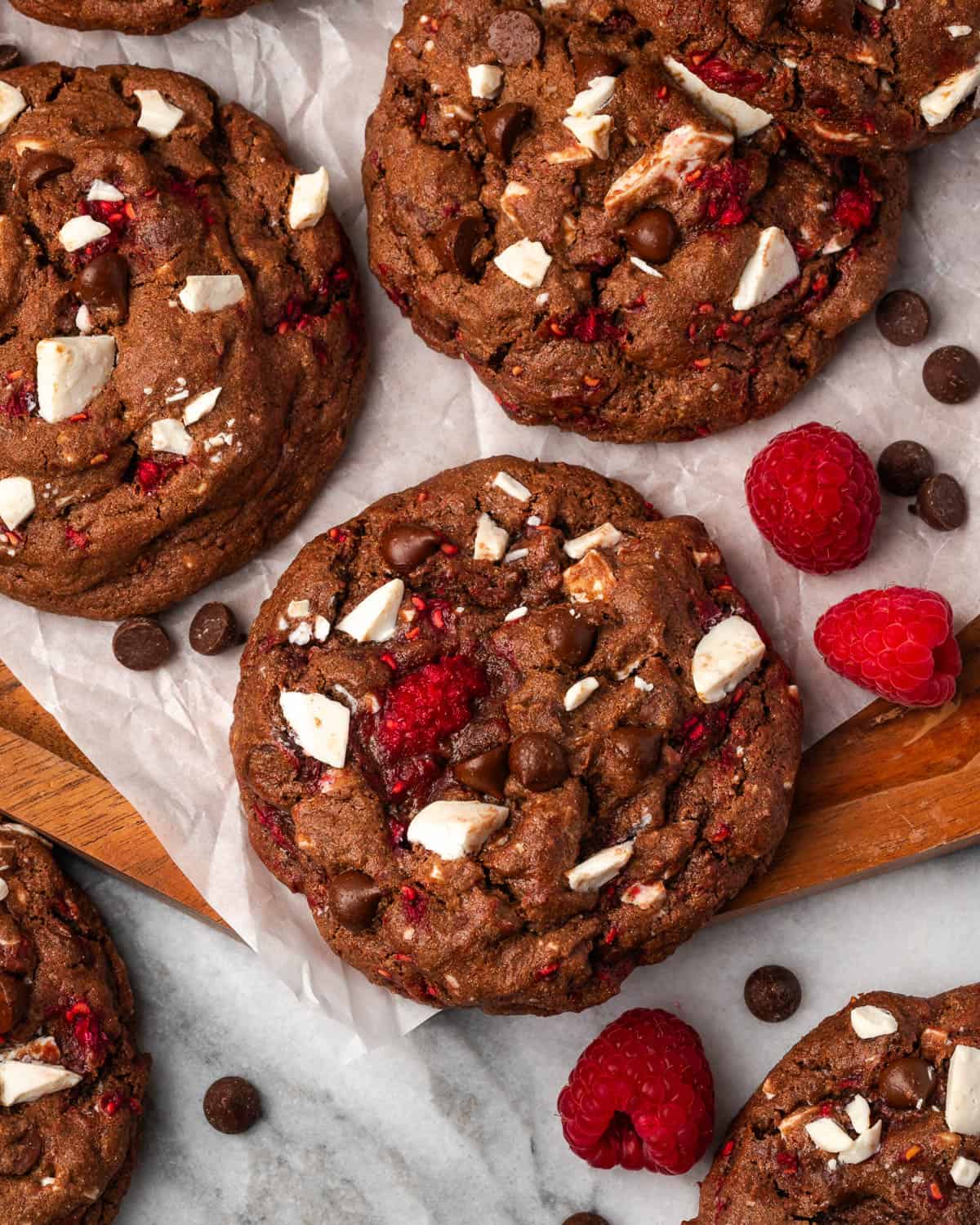 Several chocolate raspberry cookies sitting on a wood tray. 
