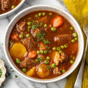 A bowl of beef stew sitting on a marble counter.