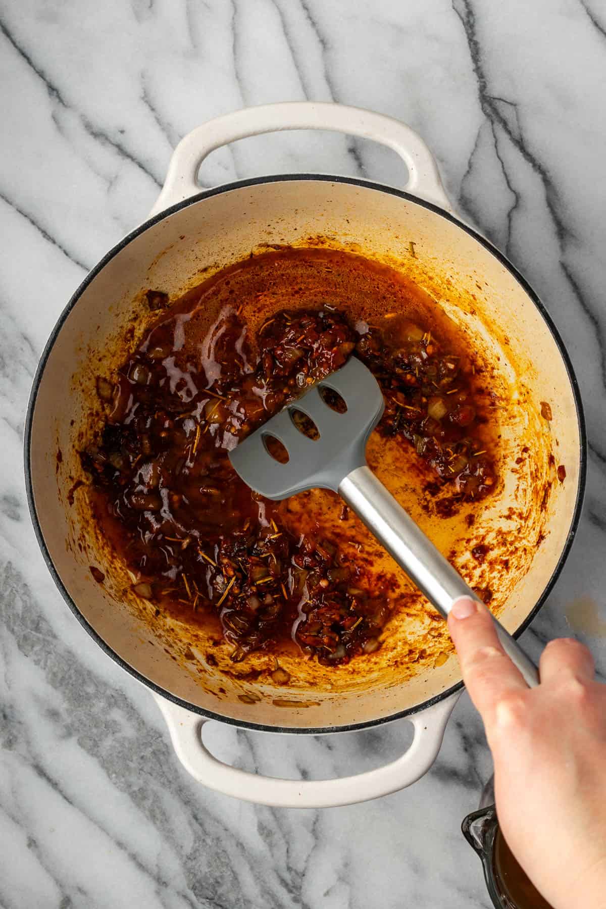 A spatula scraping the food from the bottom of the pot.