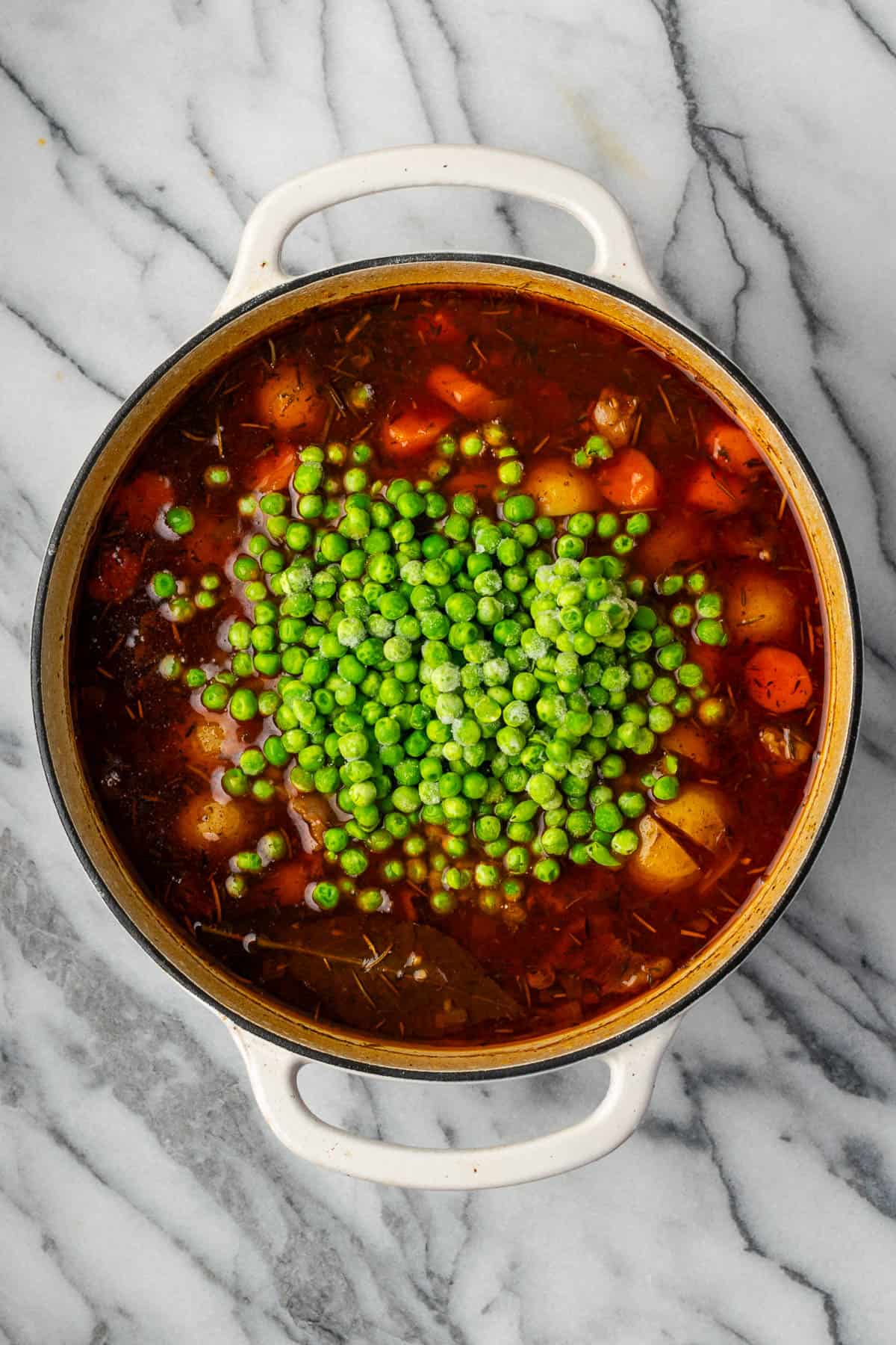 Frozen peas being added into the cooked beef stew.
