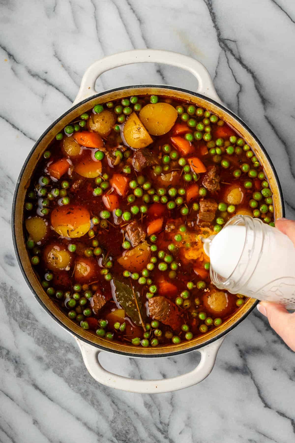 A starch slurry being stirred into the finished pot of beef stew.