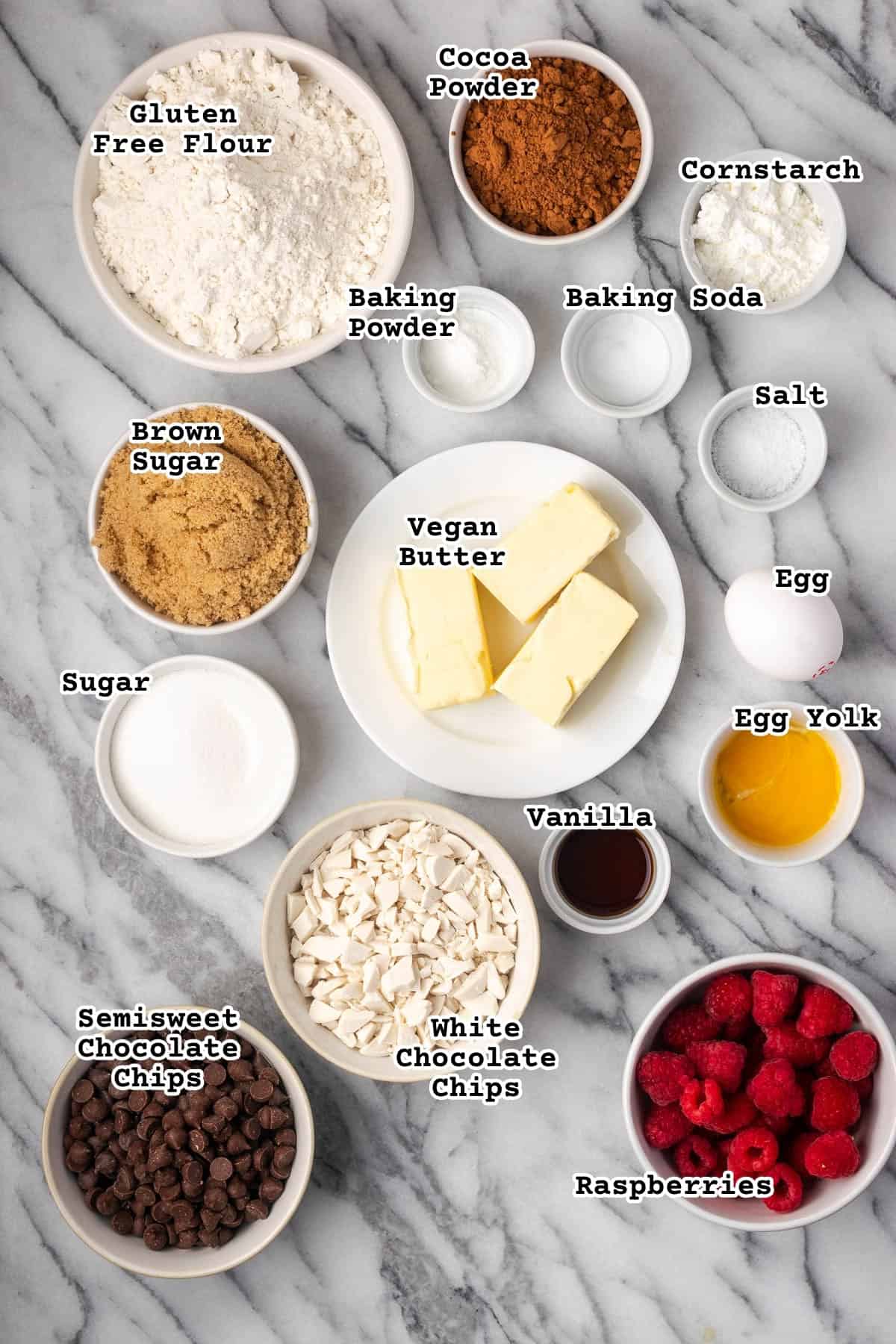 Ingredients for chocolate raspberry cookies on a marble counter.