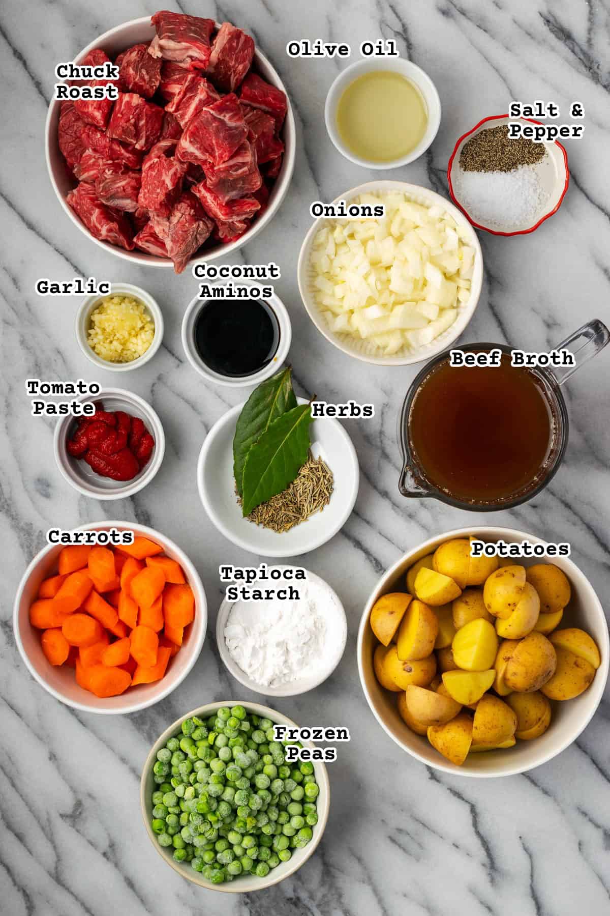 Ingredients for beef stew sitting on a marble counter.