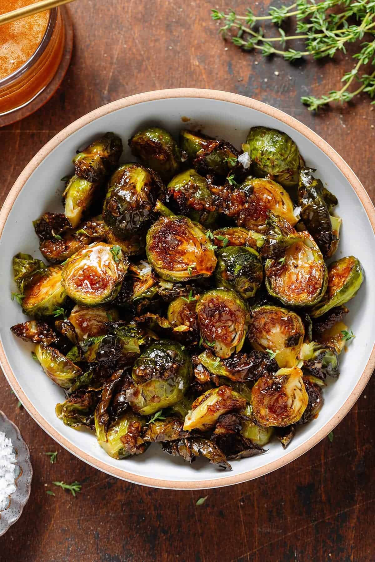 A bowl of roasted brussel sprouts sitting on a wood table.