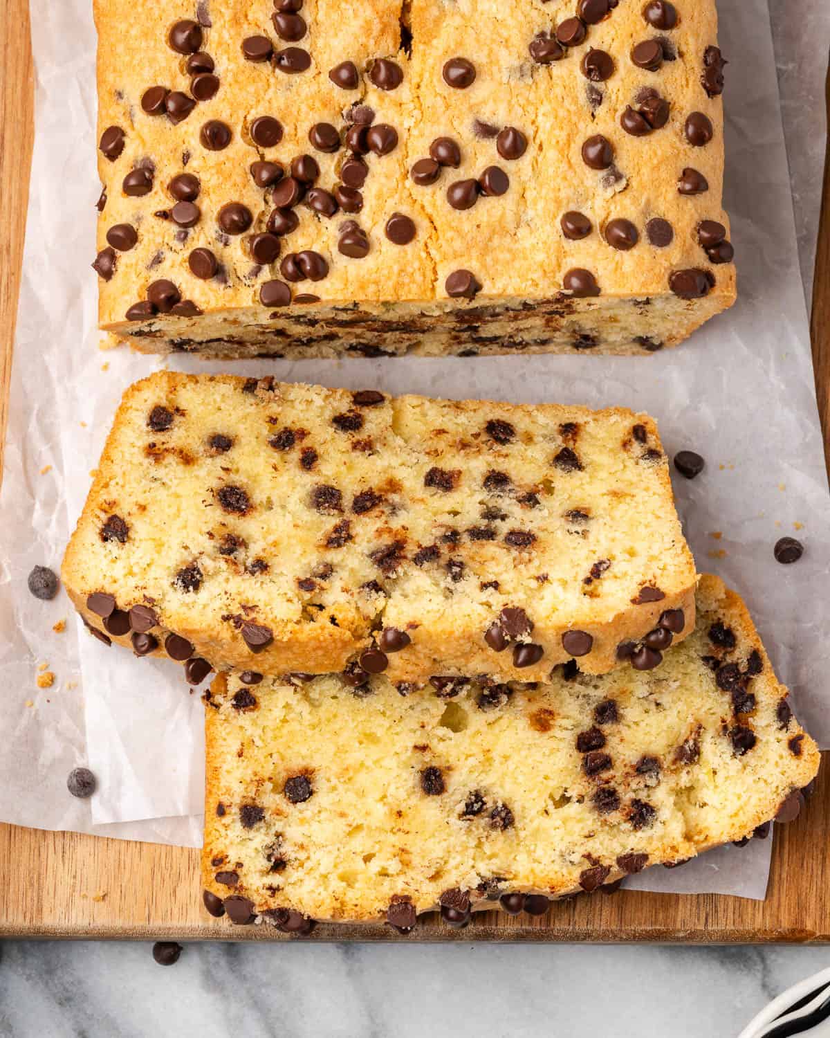 A sliced chocolate chip pound cake sitting on a wooden cutting board.