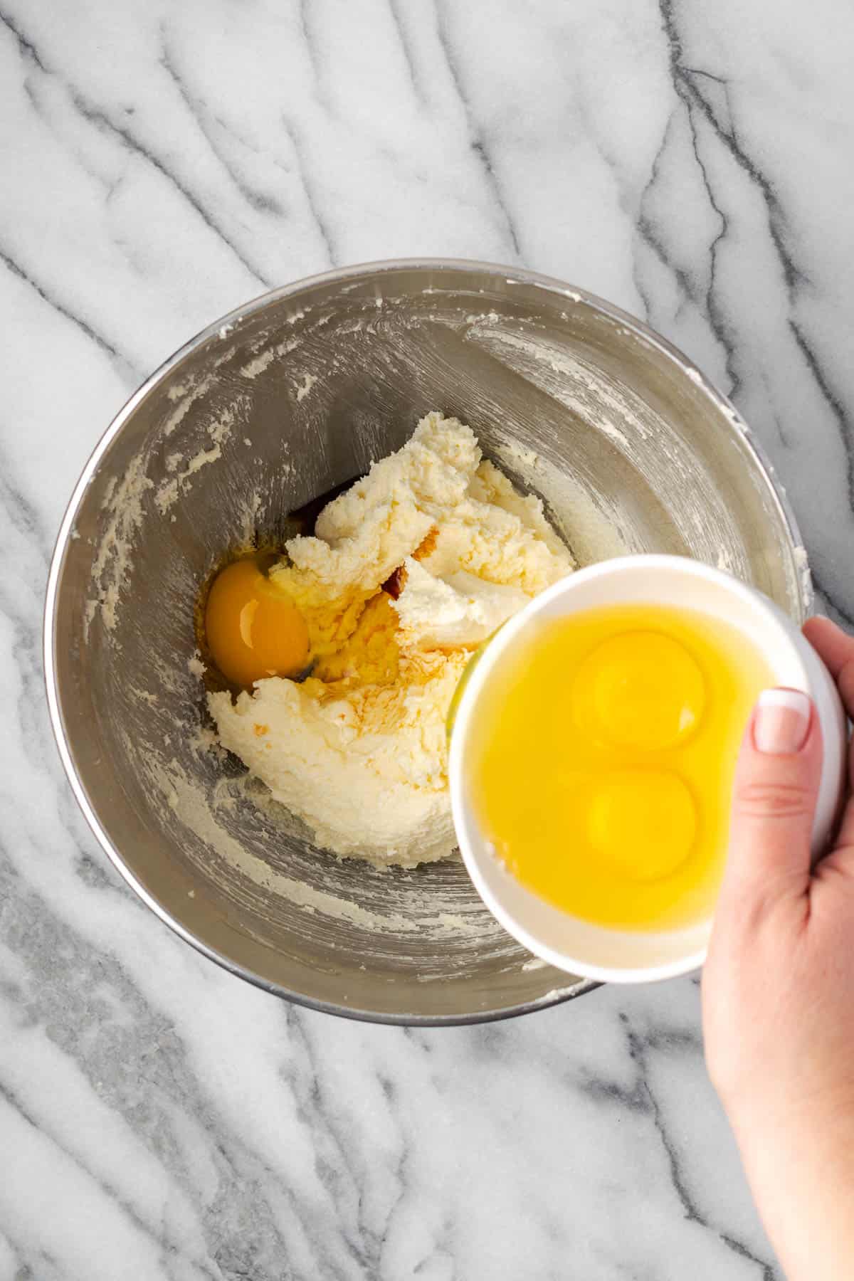 Eggs being added in the creamed butter and sugar.