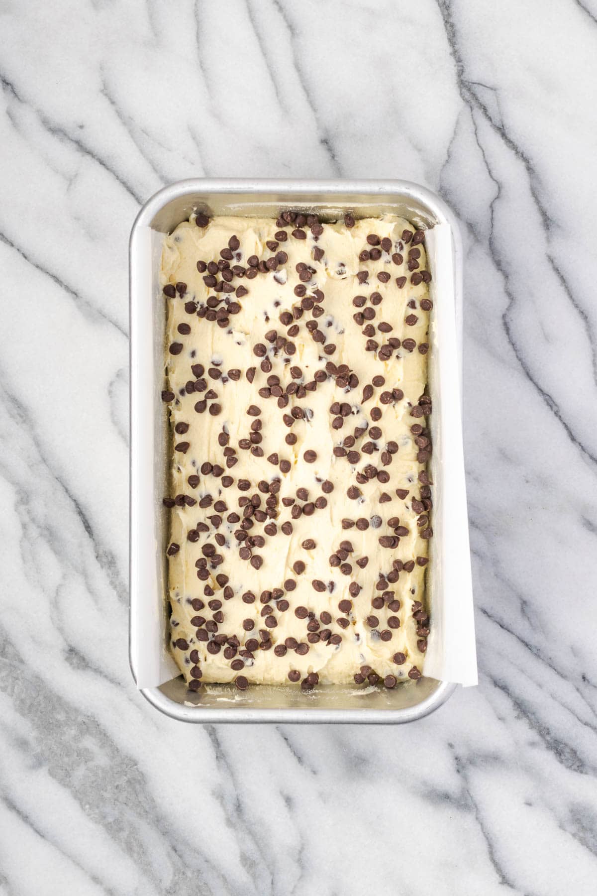 An unbaked chocolate chip pound cake in a metal baking tin.