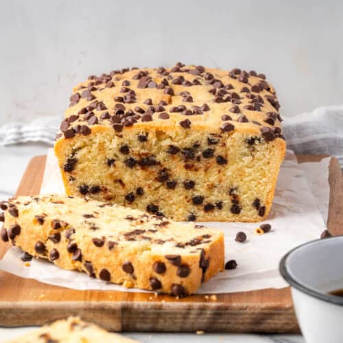 A loaf of chocolate chip pound cake cut into slices and sitting on a wood cutting board.