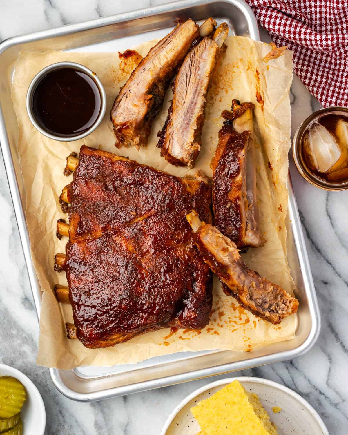 BBQ spare ribs served on a small metal tray alongside some corn bread.