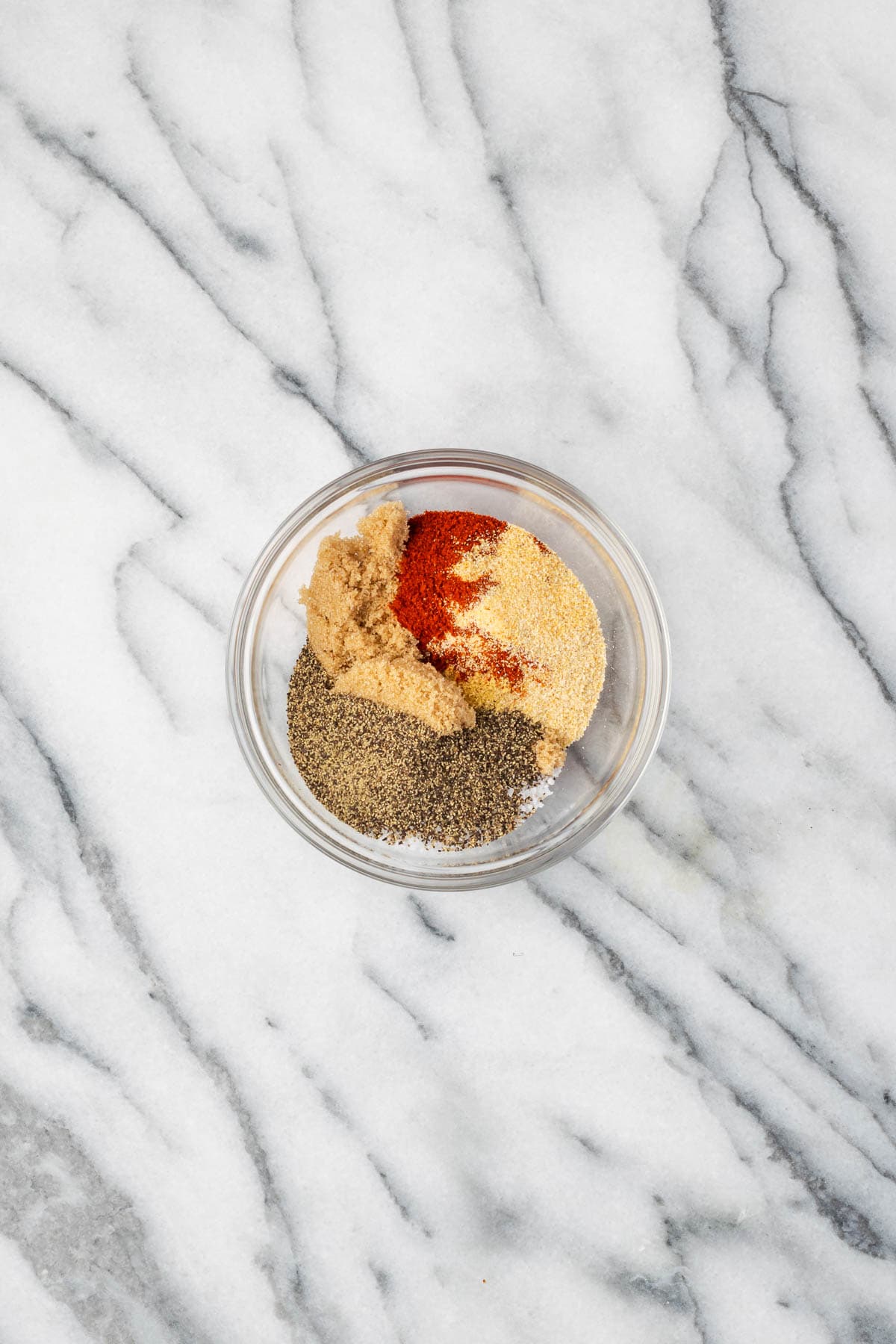 BBQ dry rub ingredients combined in a small glass bowl. 