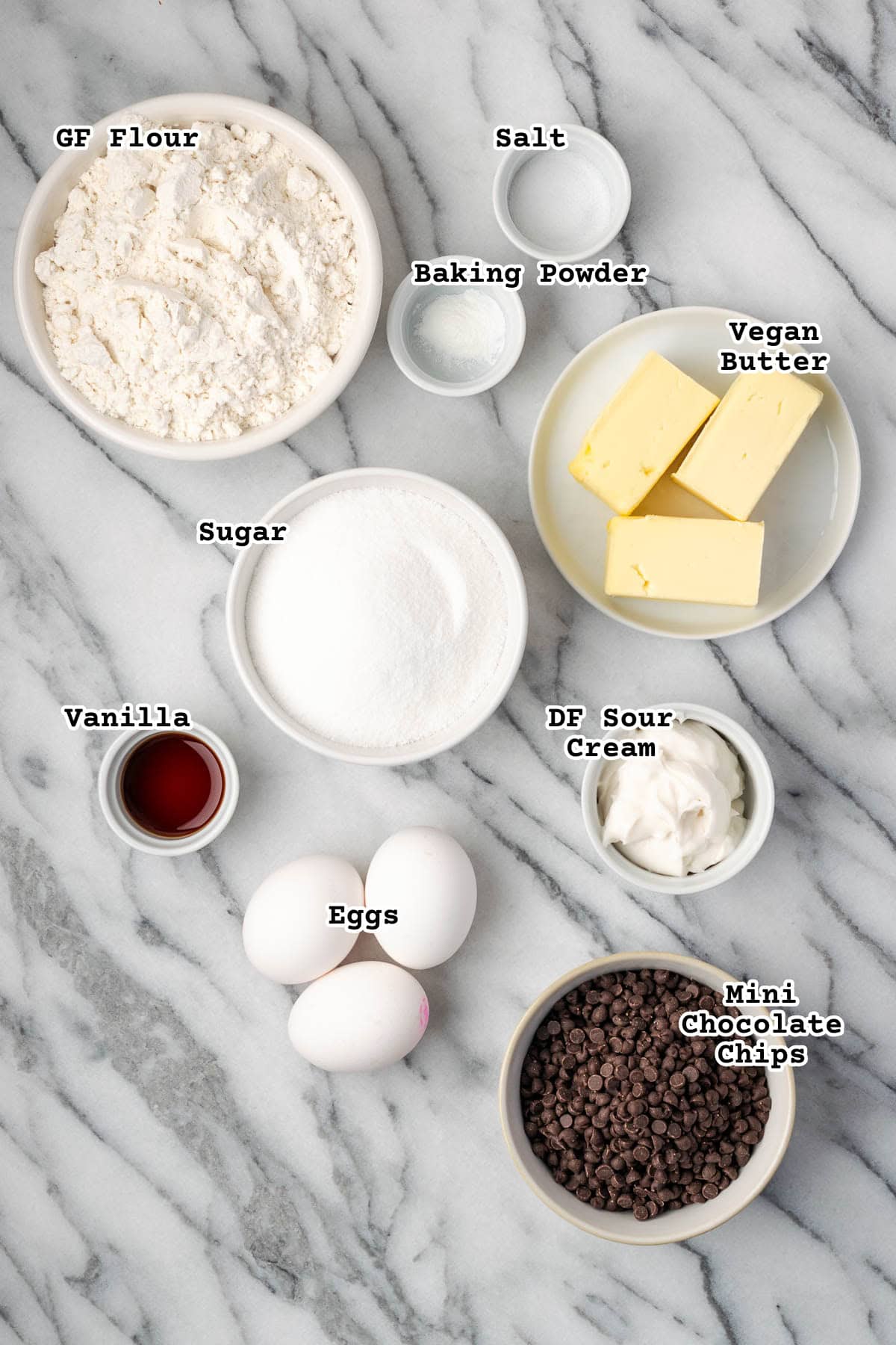Ingredients for a sour cream chocolate chip pound cake sitting on a marble counter.