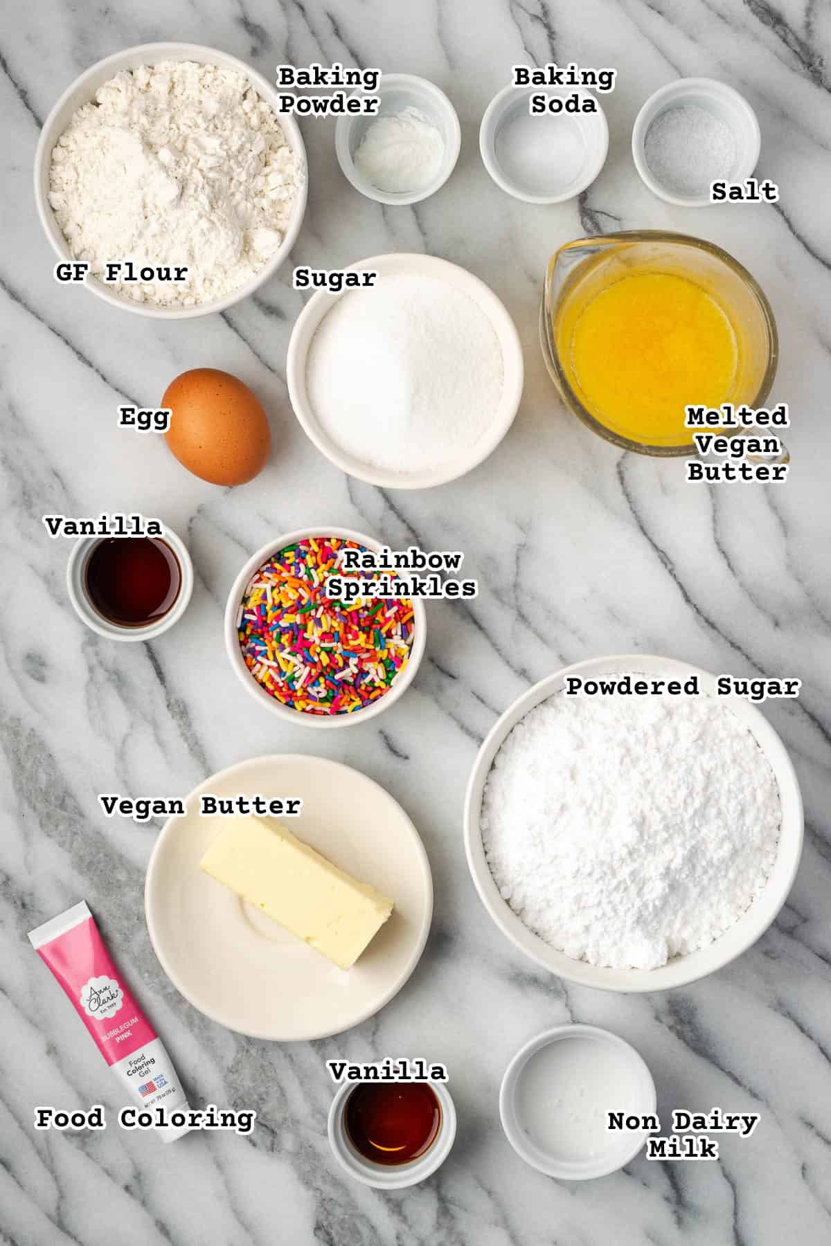 Ingredients for a sugar cookie cake with sprinkles sitting on a marble counter.