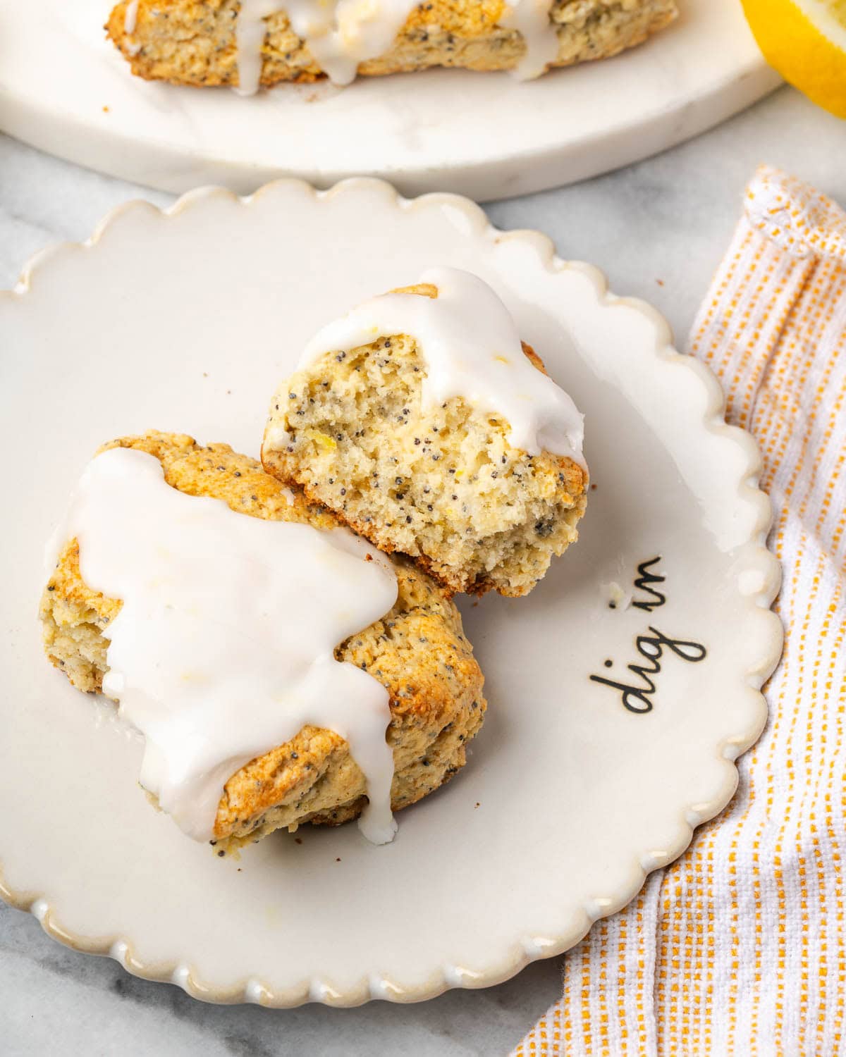 A lemon poppy seed scone broken in half sitting on a small serving plate.
