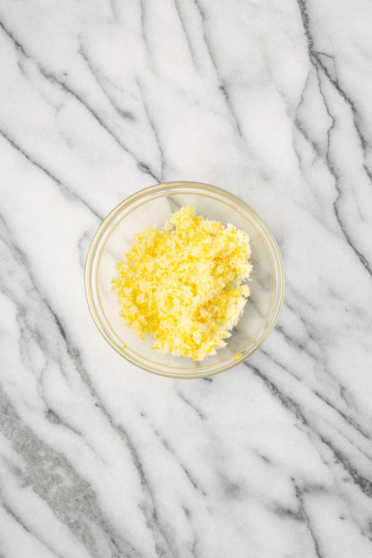 Sugar and lemon zest combined in a small glass bowl.