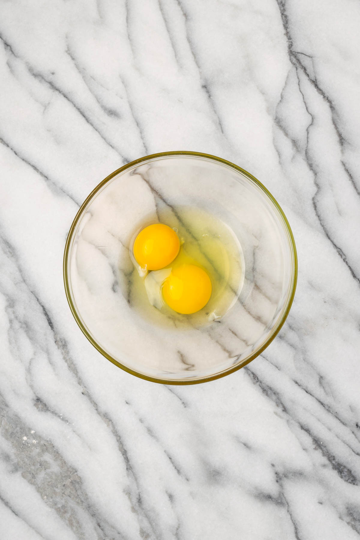 An egg and an egg yolk in a small glass bowl.