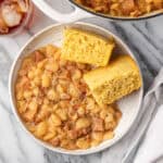 A bowl of lima beans and ham with two pieces of cornbread.