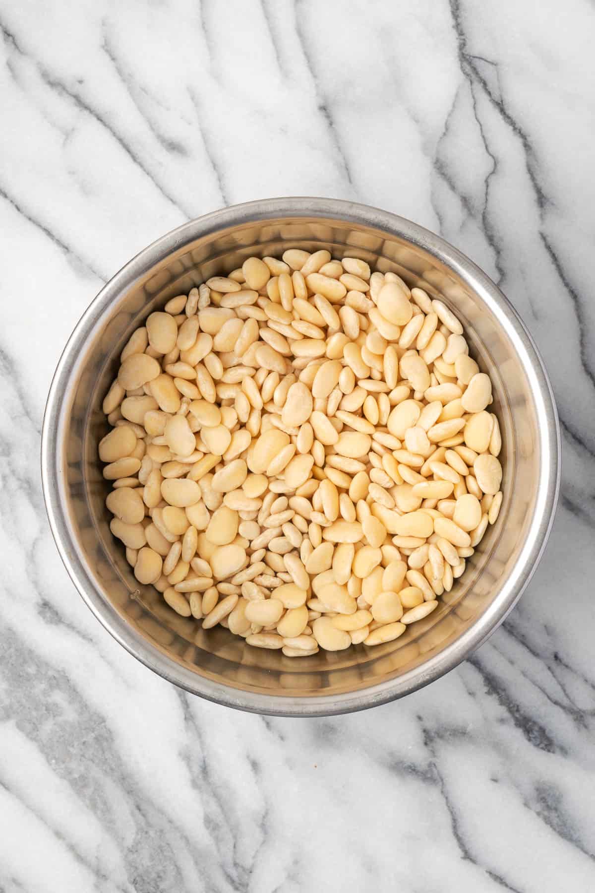 Dried lima beans soaking in a bowl of water.