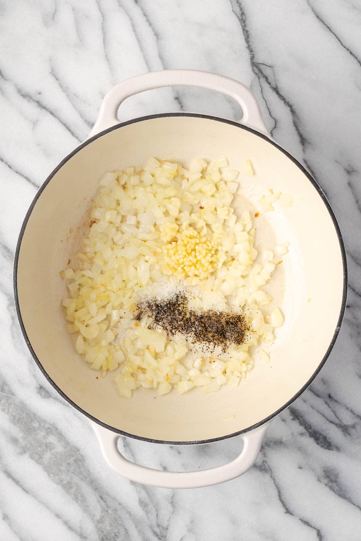 Minced garlic, salt and pepper added to the pot with the partially cooked onions. 