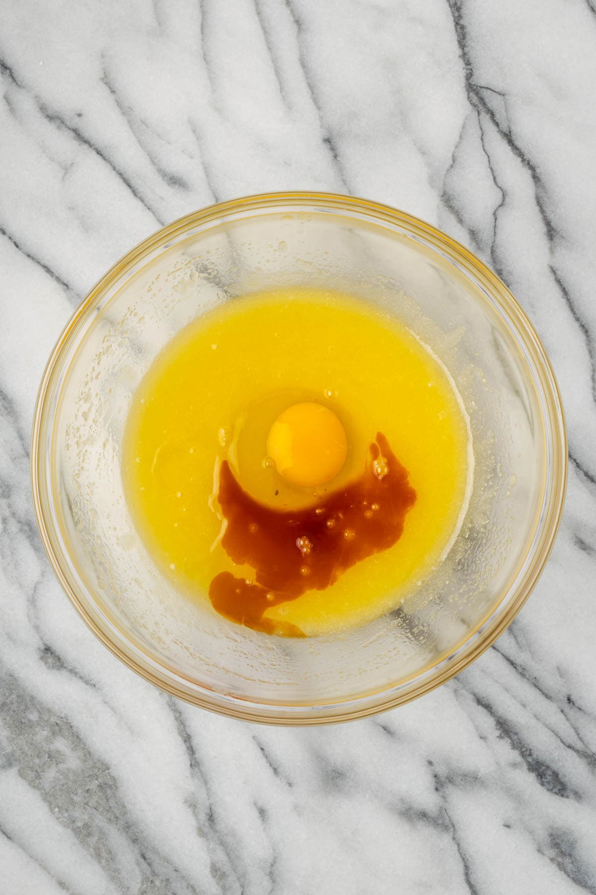 An egg and vanilla extract added to the mixing bowl.