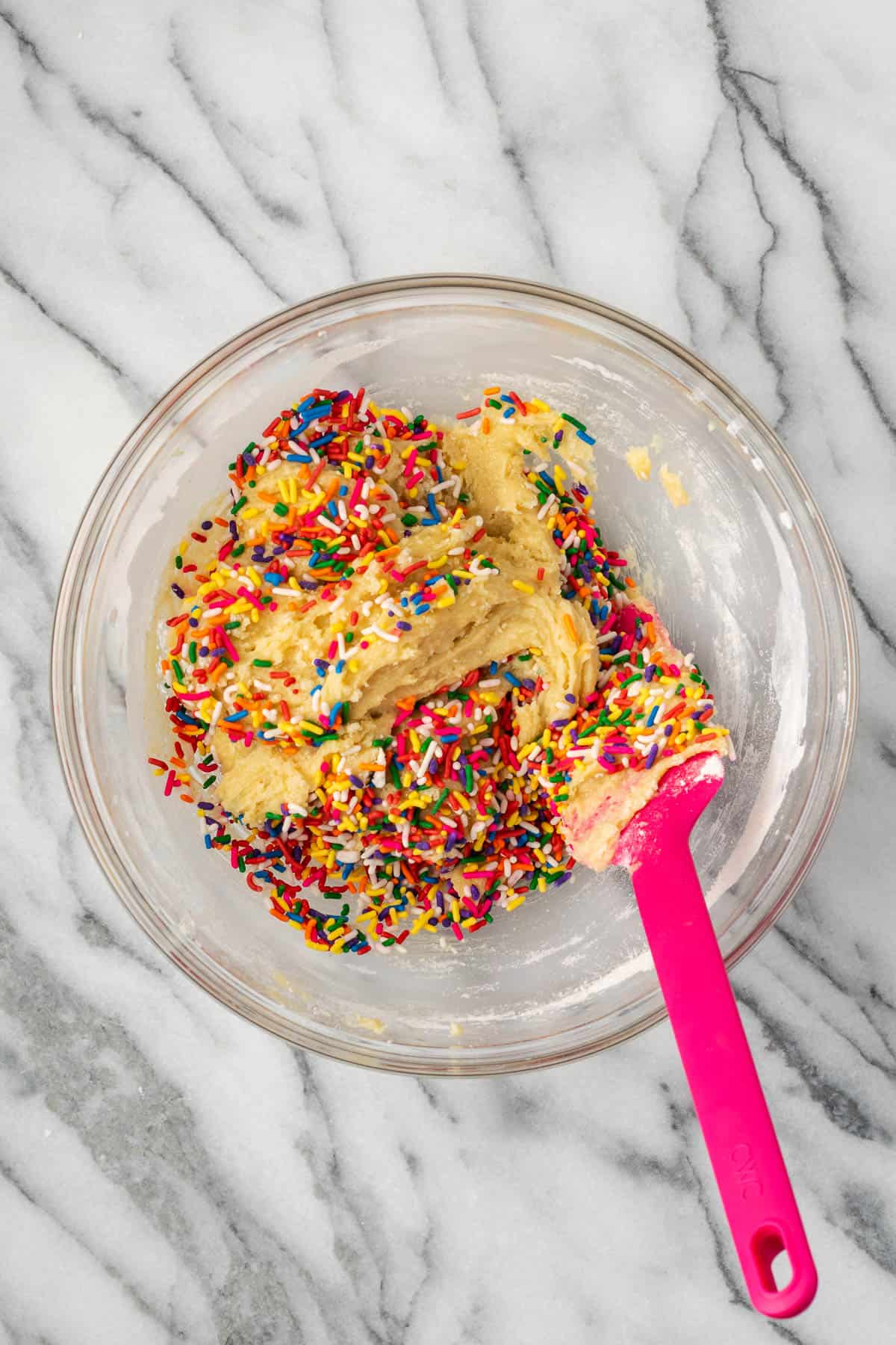 Sprinkles being stirred into the sugar cookie dough.
