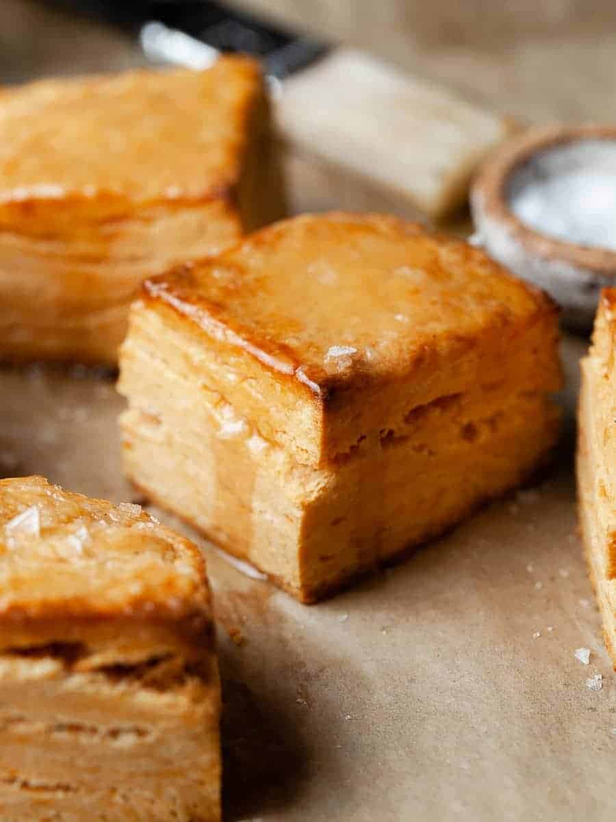 Several gluten free sweet potato biscuits drizzled with honey sitting on a baking sheet.