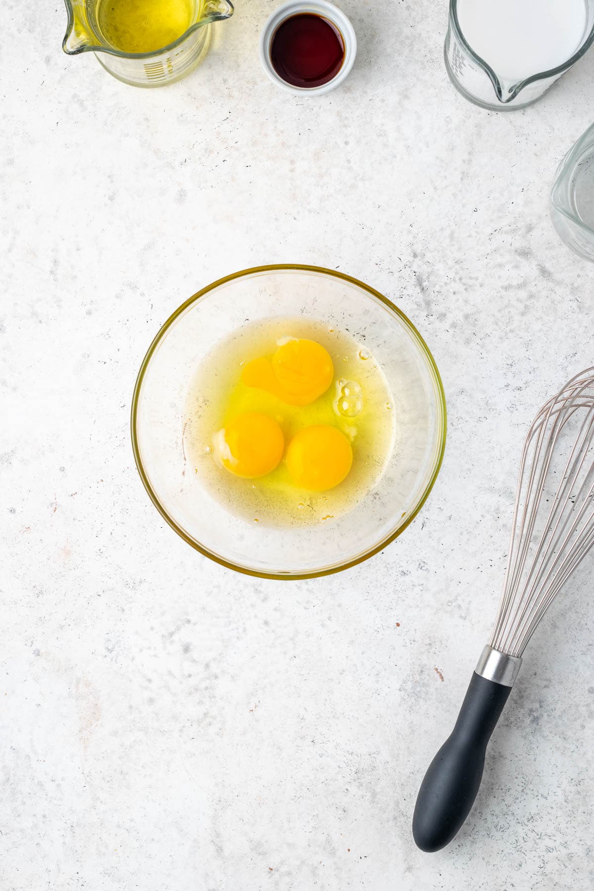 Three eggs cracked into a medium  sized glass bowl.