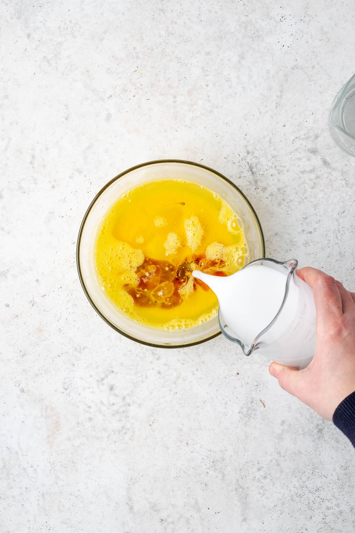 Oil, vanilla extract and milk being combined with the beaten eggs.
