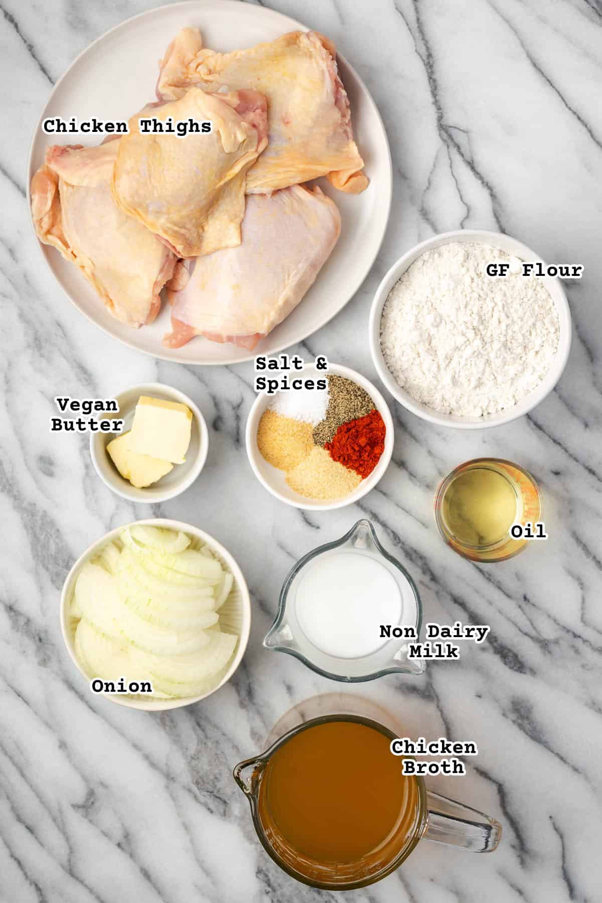 Ingredients for smothered chicken thighs sitting on a marble counter.