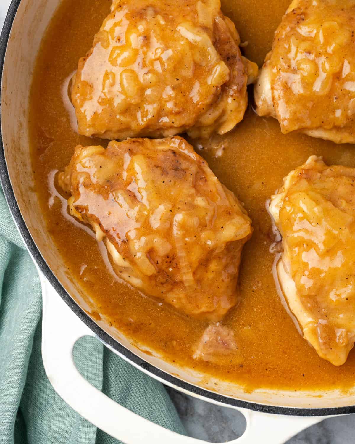Chicken thighs smothered in onion gravy in a large cast iron skillet.