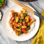 Teriyaki chicken and vegetables served over white rice in a bowl sitting on a marble counter.