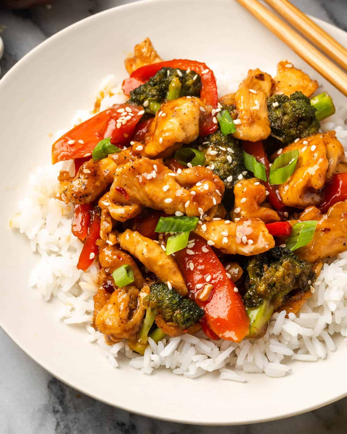 A bowl of chicken teriyaki with vegetables served over white rice.
