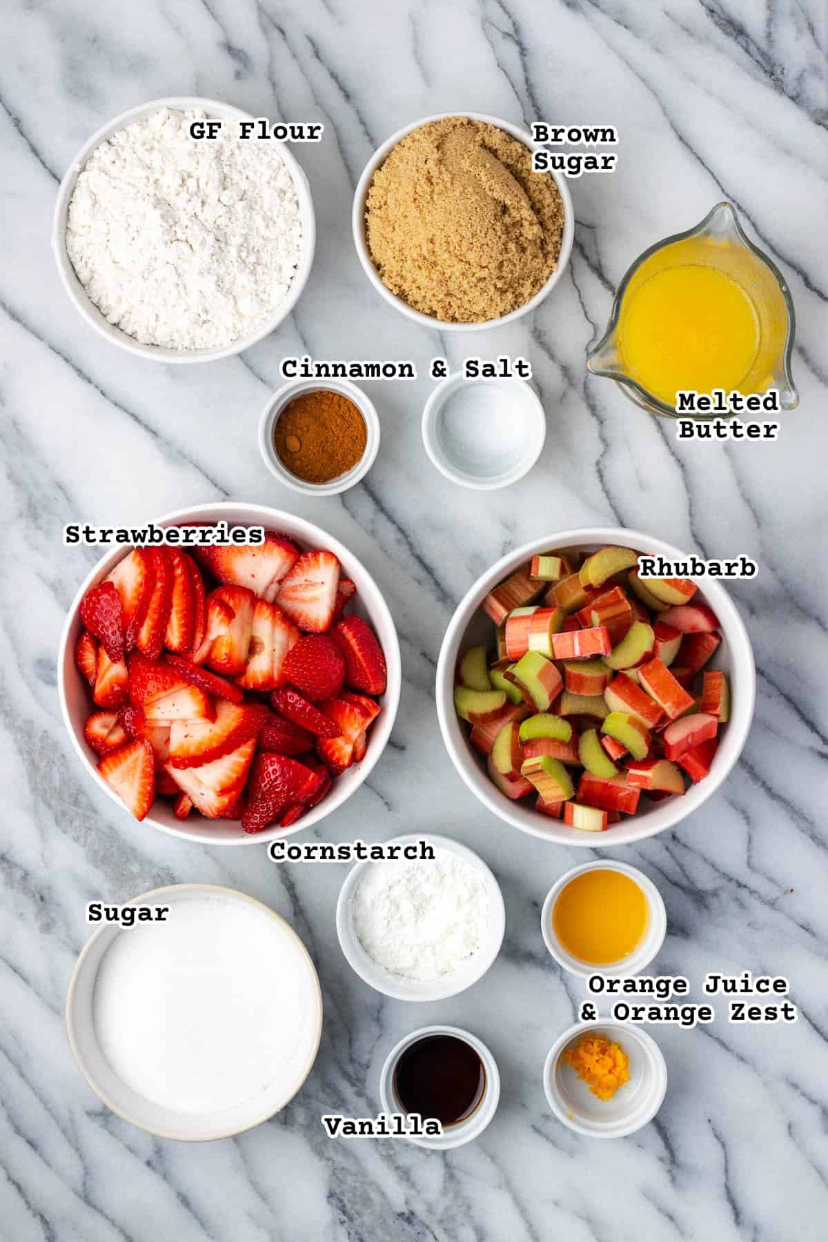Ingredients for a strawberry rhubarb crumble sitting on a marble counter.