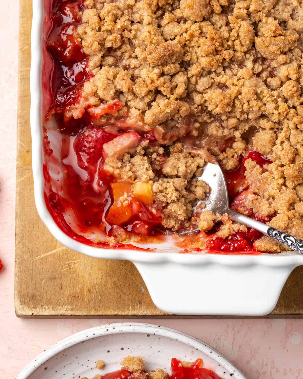 A spoon scooping into a strawberry rhubarb crumble.