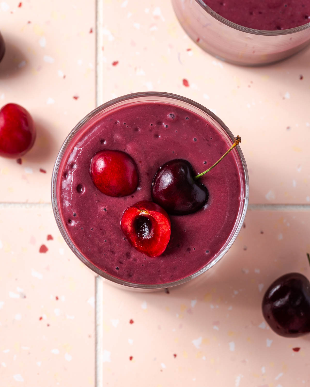 A cherry smoothie topped with a few fresh cherries.