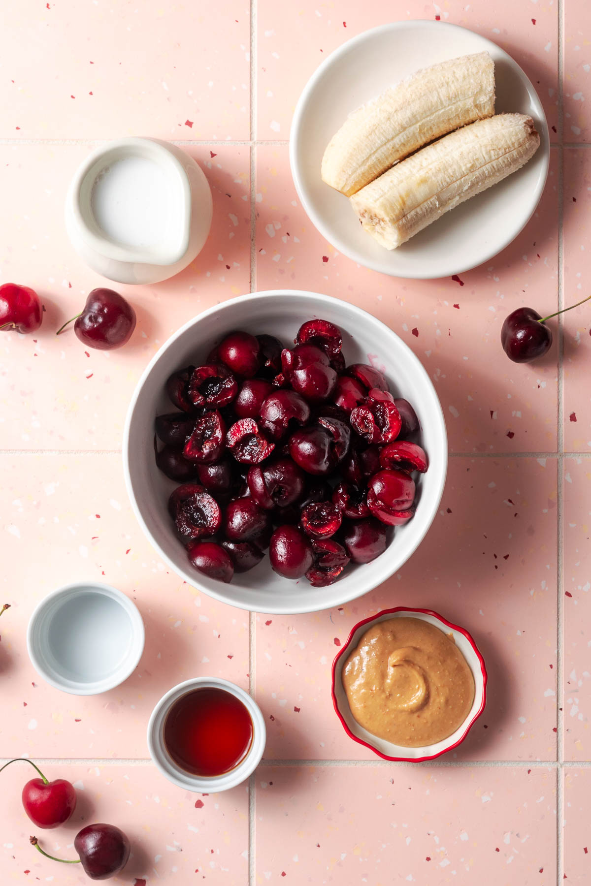 Ingredients for a sweet cherry smoothie sitting on a tile counter.